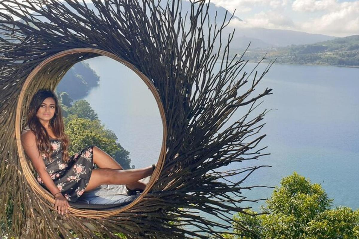 Una mujer sentada en una silla de mimbre frente a un espejo redondo.