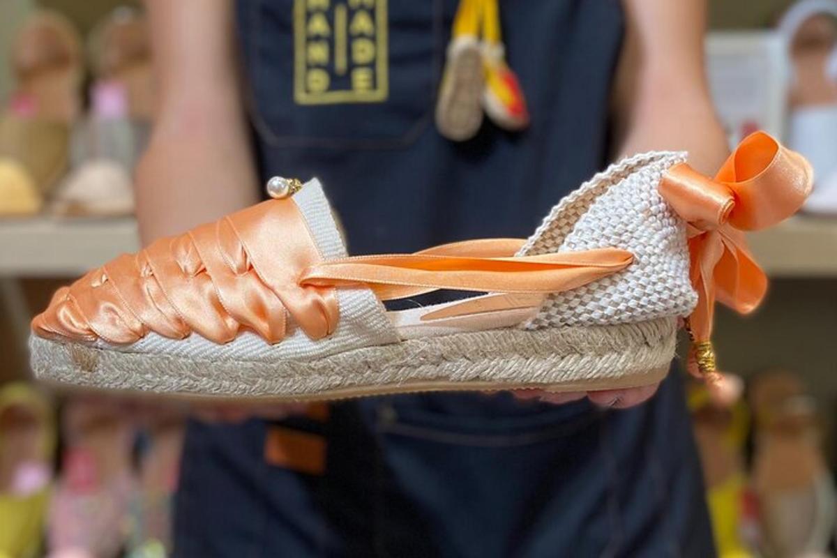 uma pessoa segurando um par de sapatos com um laço laranja