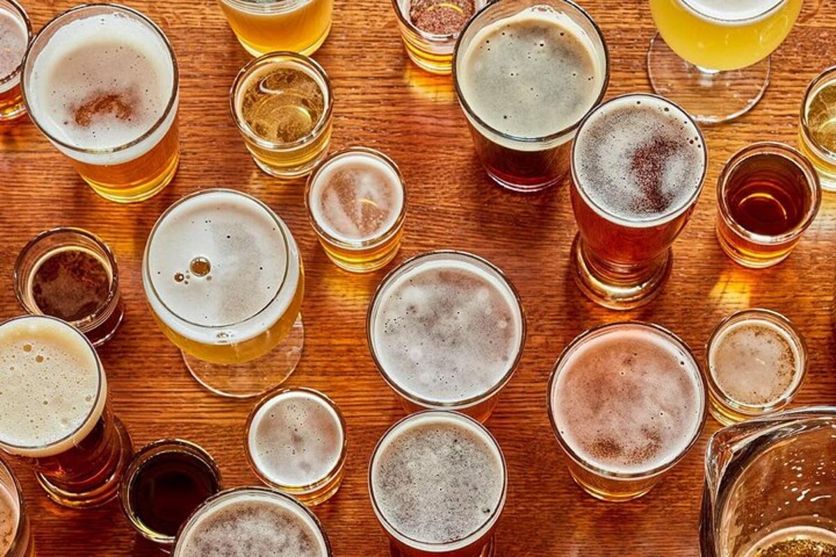 Un montón de vasos de cerveza sobre una mesa de madera.