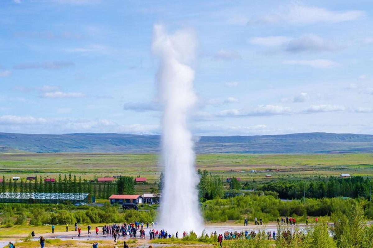 un geyser in un campo con una folla di persone