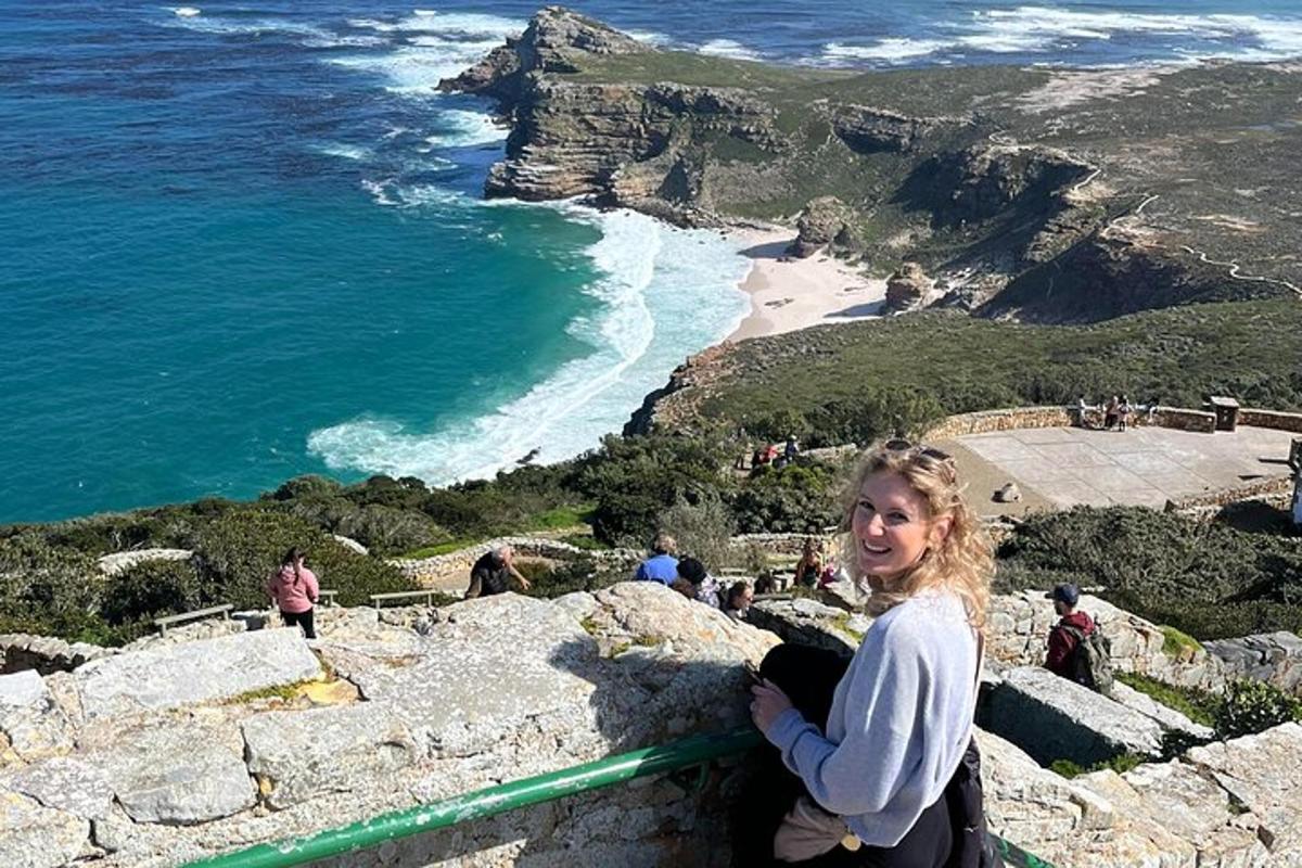 Una mujer parada en una cornisa con vista al océano