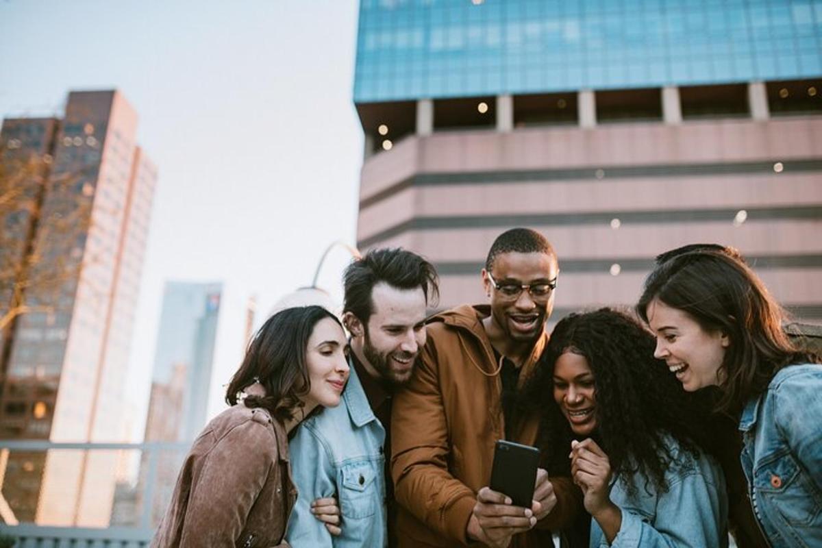 a group of people standing together looking at a cell phone