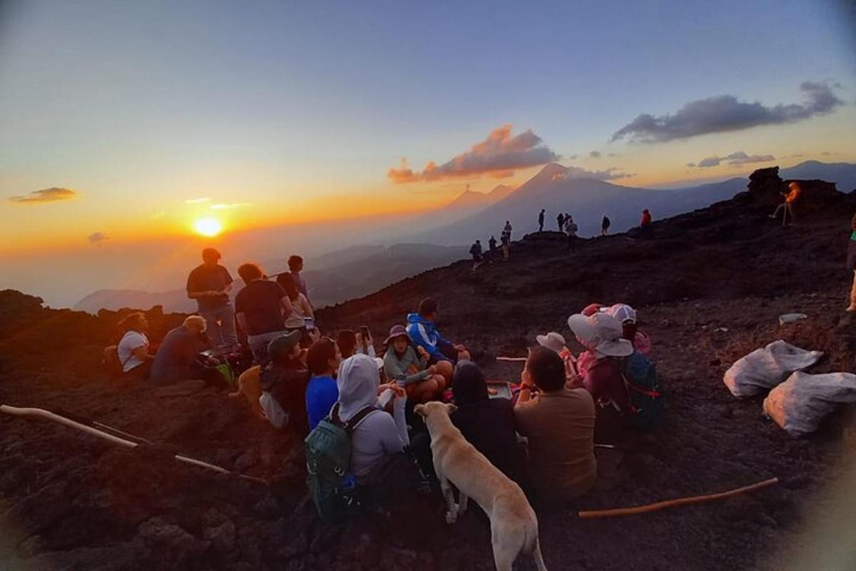 a group of people sitting on a hill watching the sunset