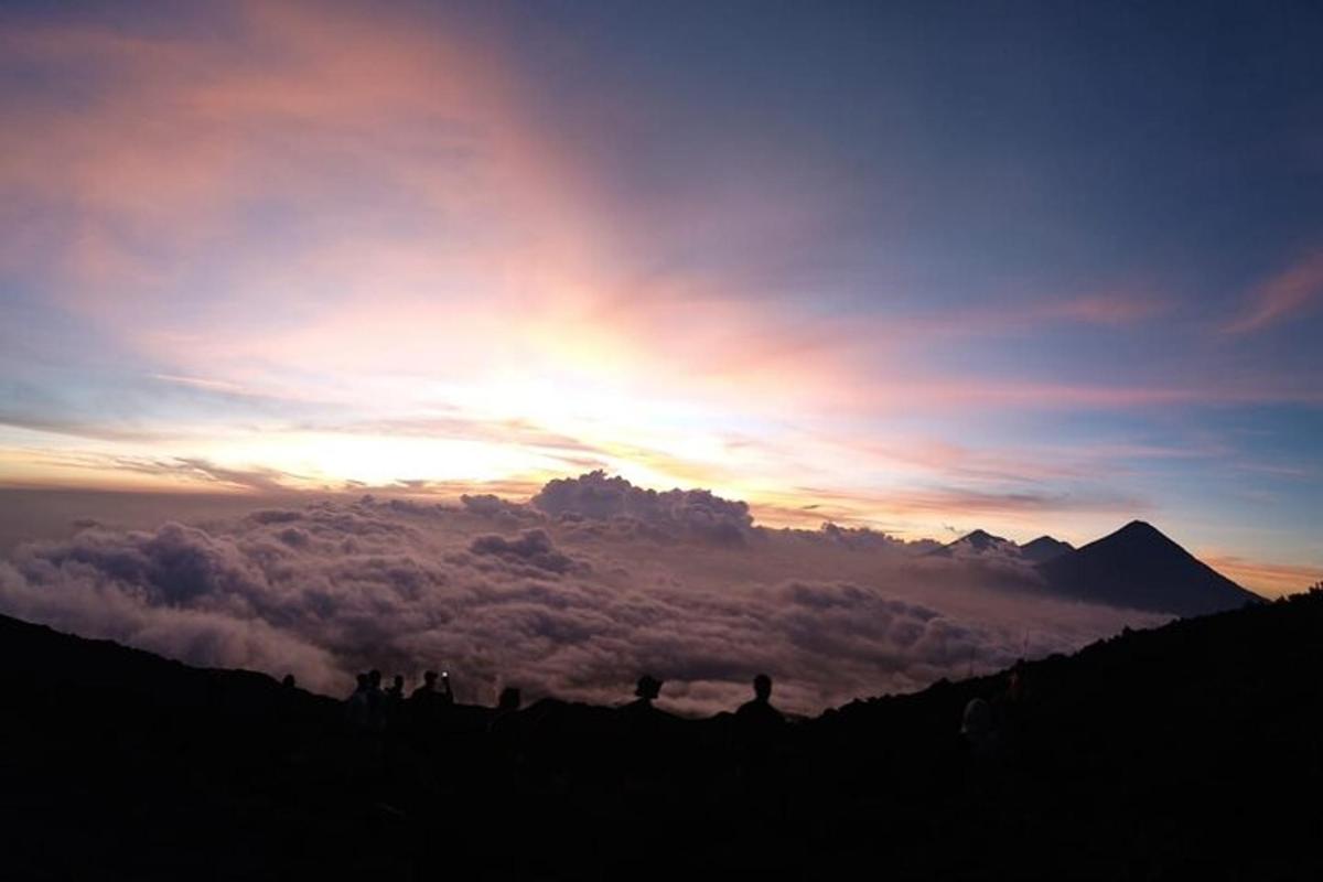 a group of people standing on top of a mountain at sunset