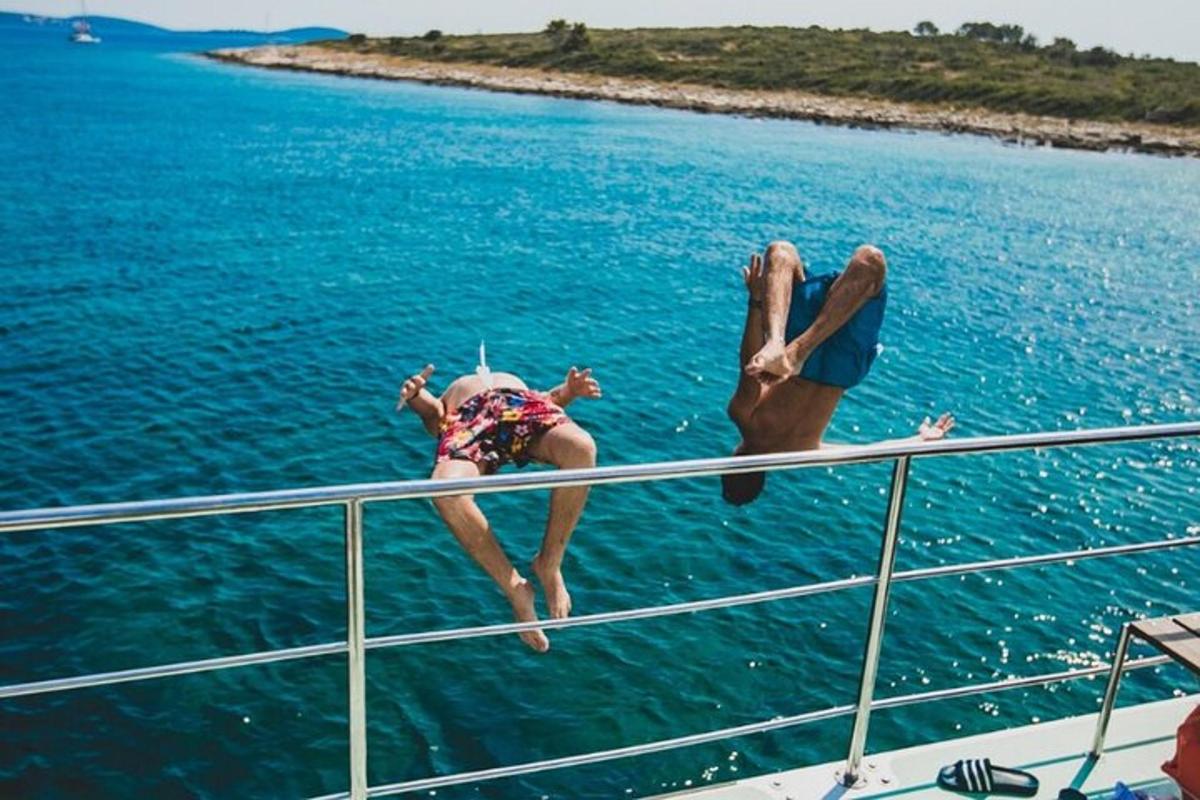 two people jumping off of a boat in the water