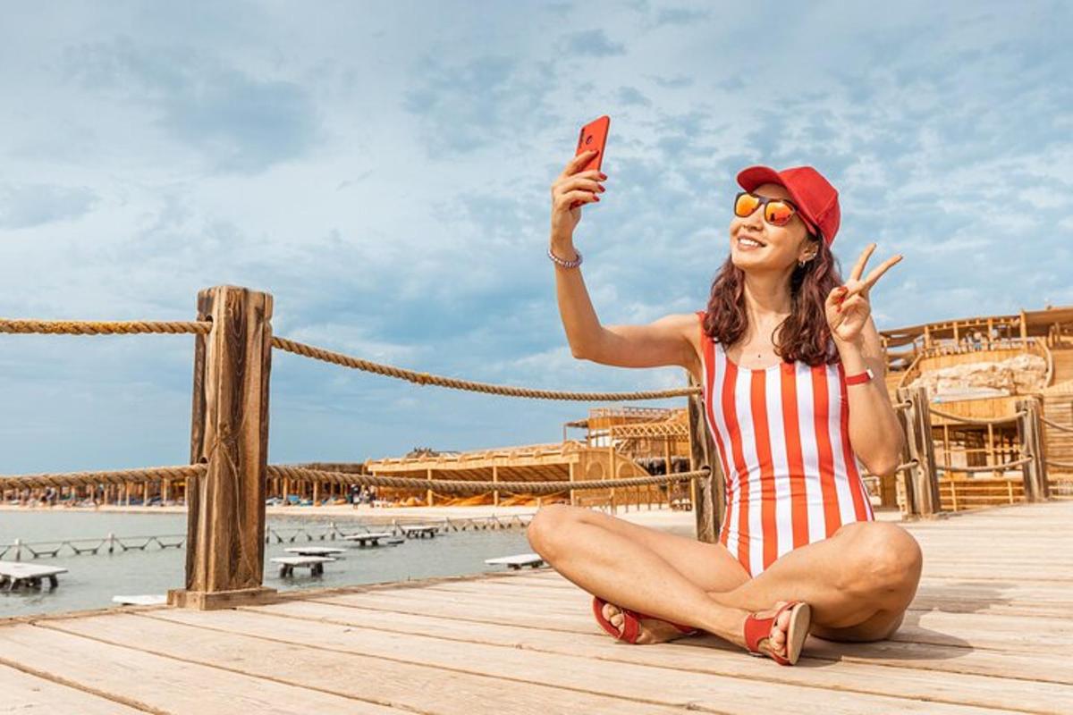 ženska sedi na pomolu in fotografira s svojim mobilnim telefonom