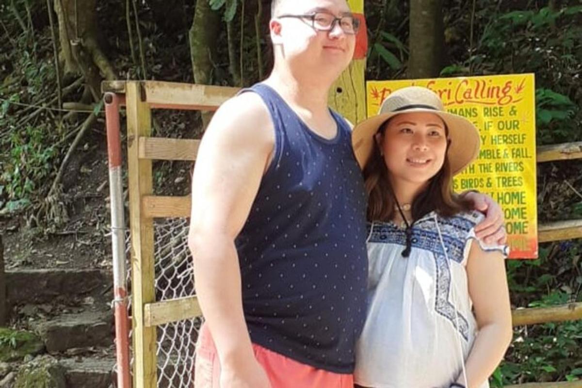 a man and a woman standing in front of a fence