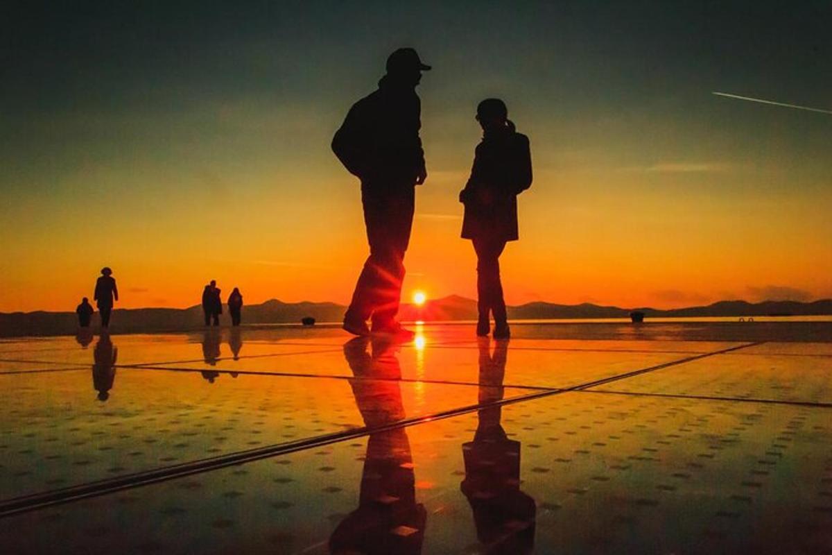 een groep mensen die bij zonsondergang op het strand staan