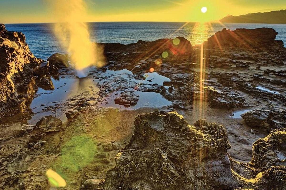 um pôr do sol sobre uma praia rochosa com o oceano