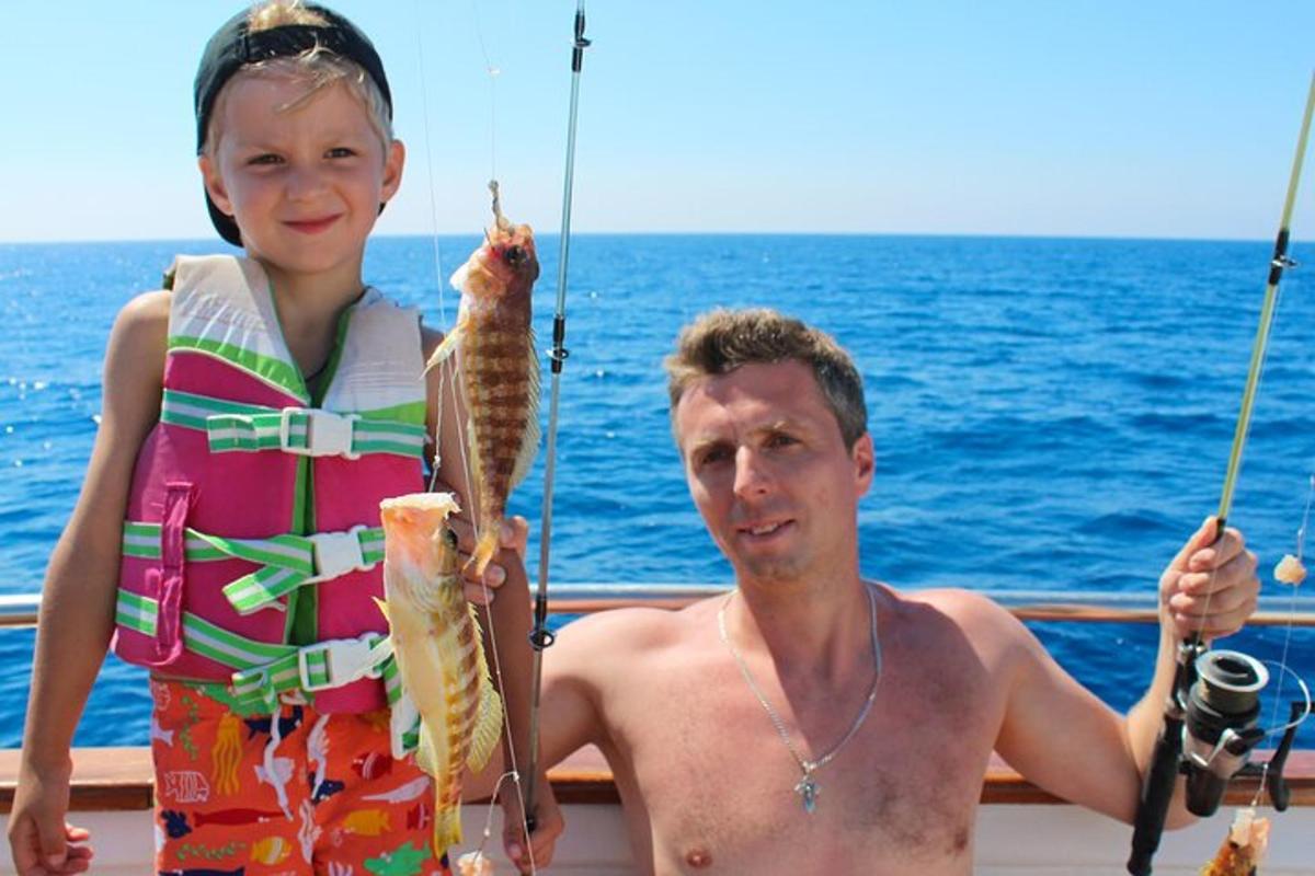 un uomo e una bambina che tengono in mano un pesce su una barca