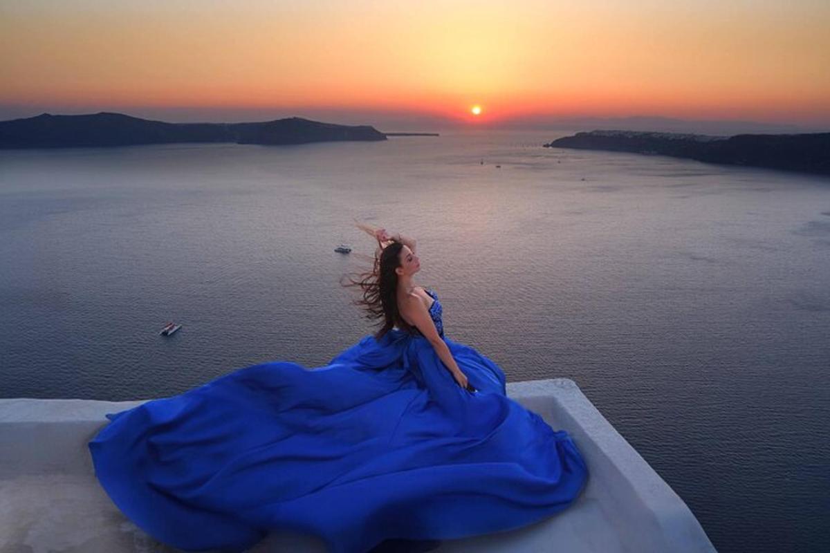 a woman in a blue dress looking at the sunset