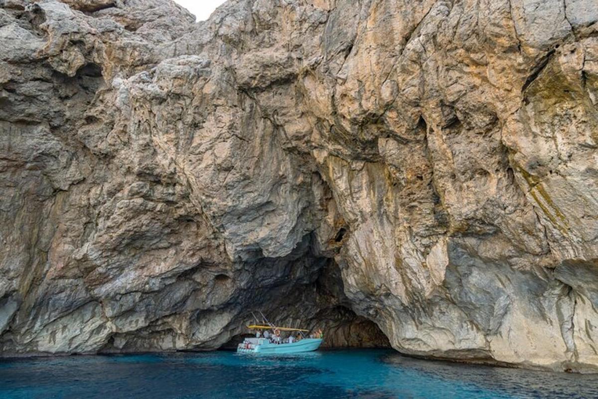 лодка в воде рядом со скалистым утесом