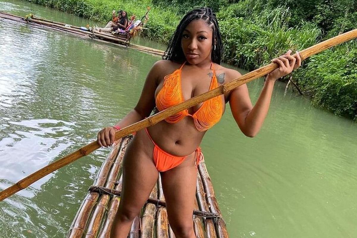 Una mujer en bikini naranja está remando en un bote.