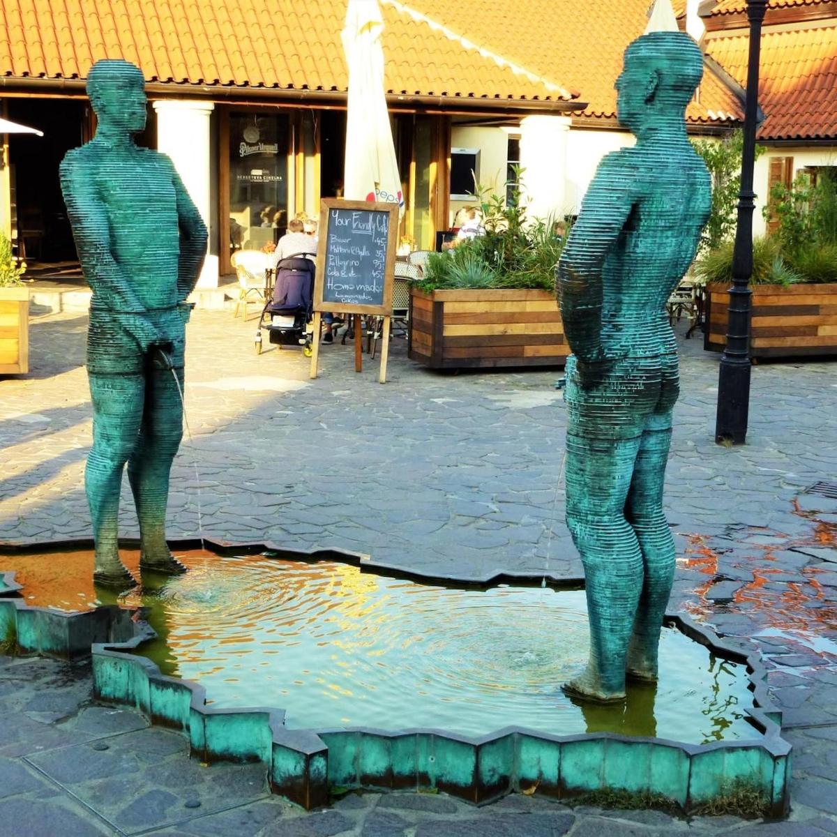 Dos estatuas de hombres de pie en un estanque de agua