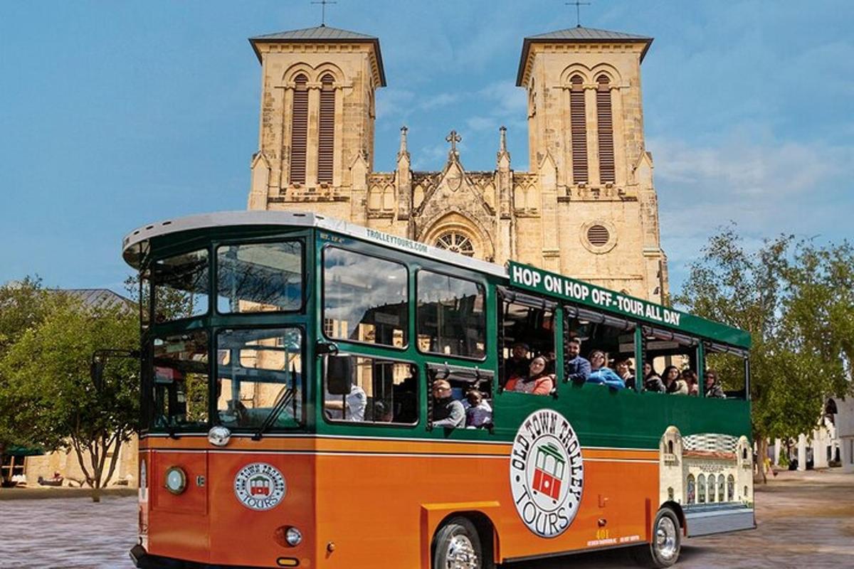 an orange and green bus in front of a church
