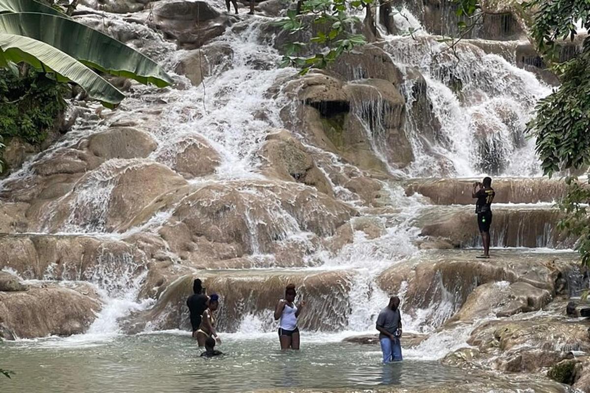 um grupo de pessoas em pé na água perto de uma cachoeira