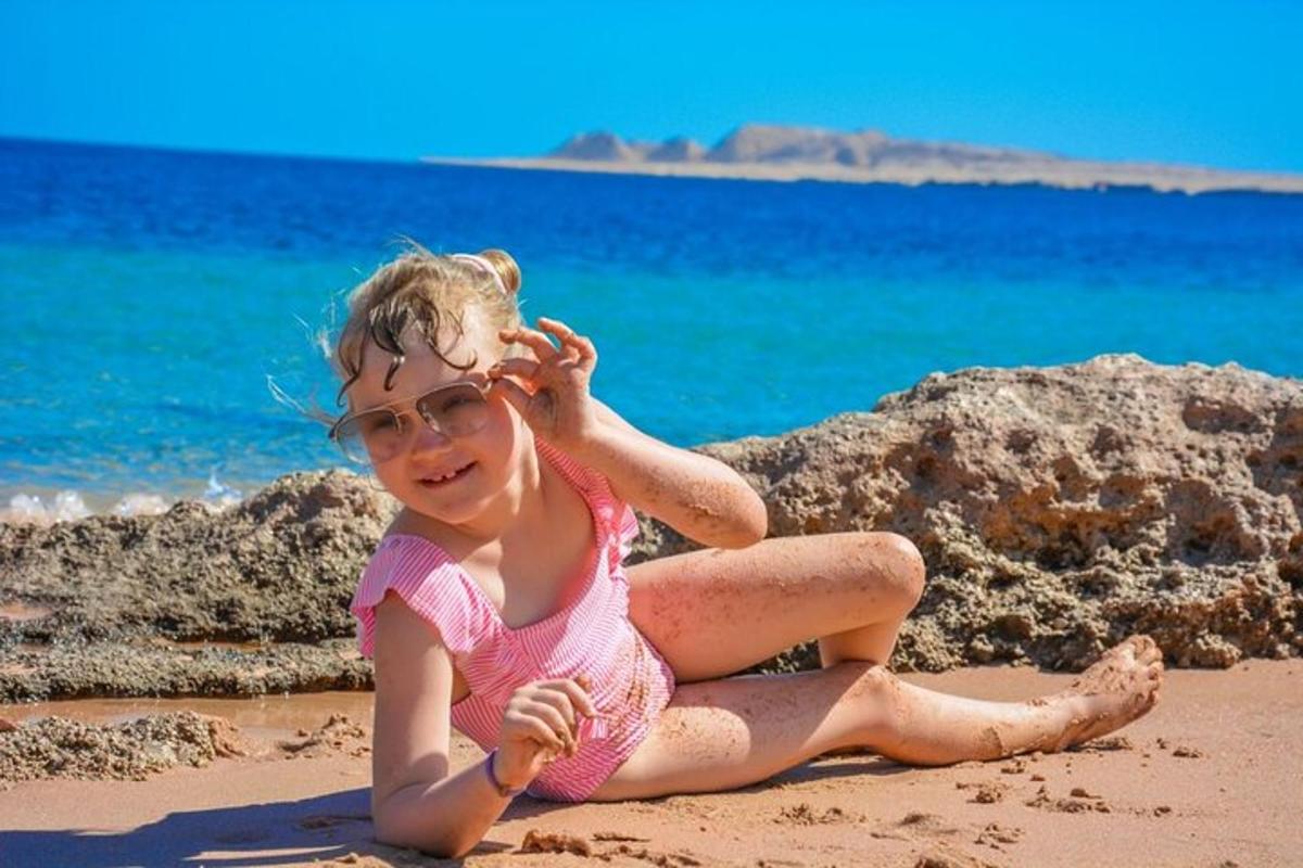una bambina seduta sulla sabbia in spiaggia