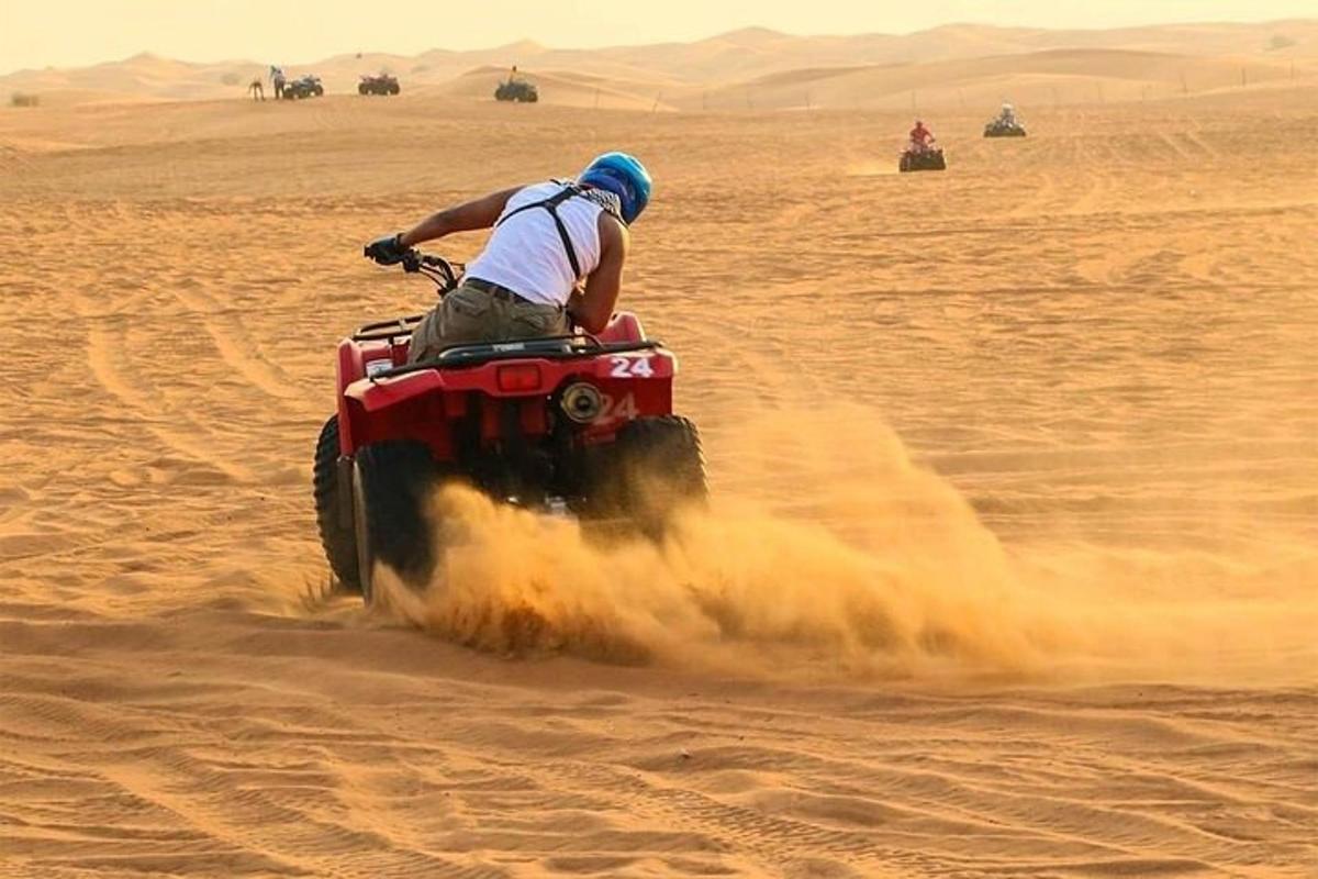 seorang lelaki menunggang basikal quad di padang pasir