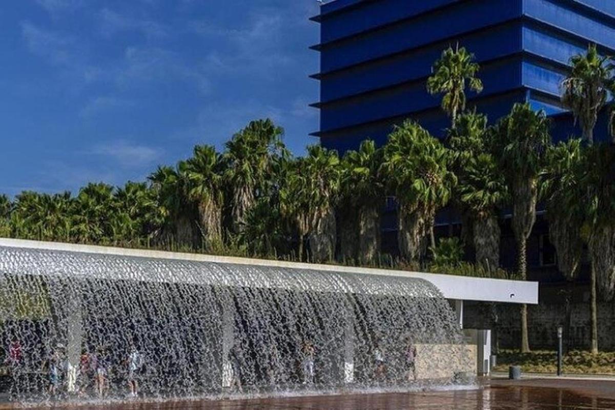 a fountain in front of a building with palm trees