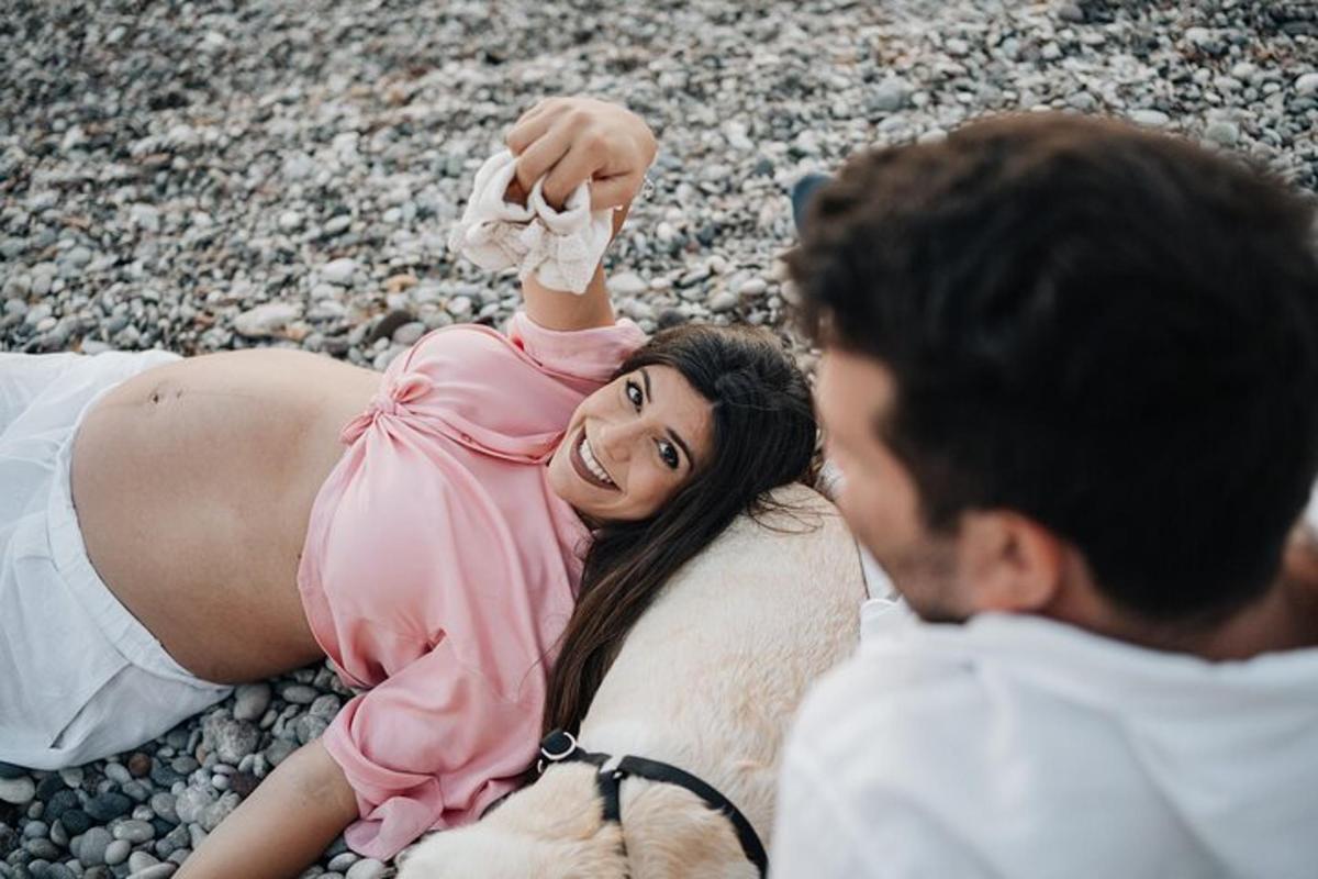 ženska v roza obleki leži na plaži z moškim