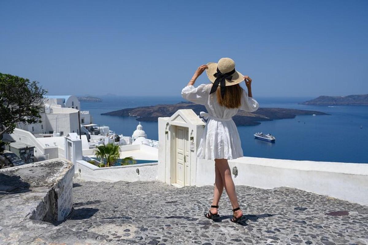a woman in a white dress and hat looking at the ocean