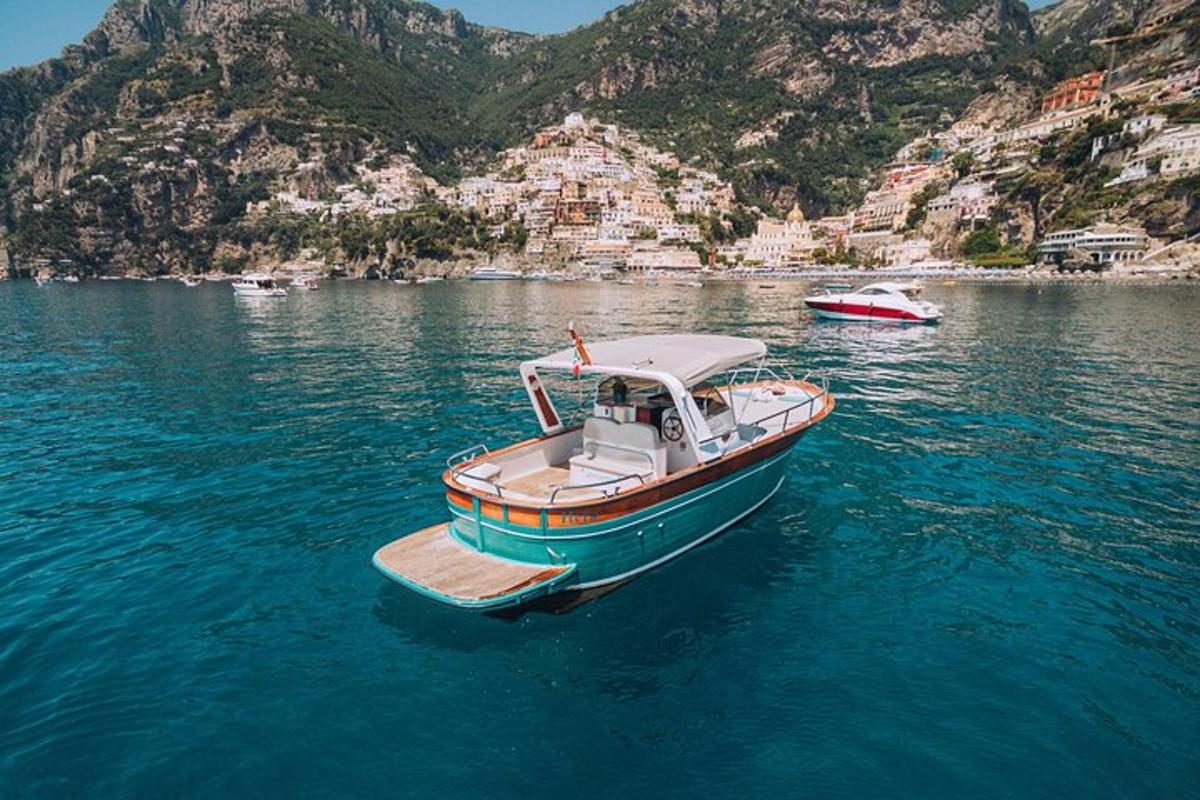 a small boat floating in the water near a mountain