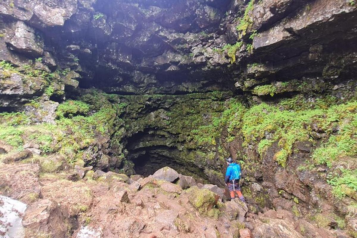 a person standing on some rocks in front of a cave