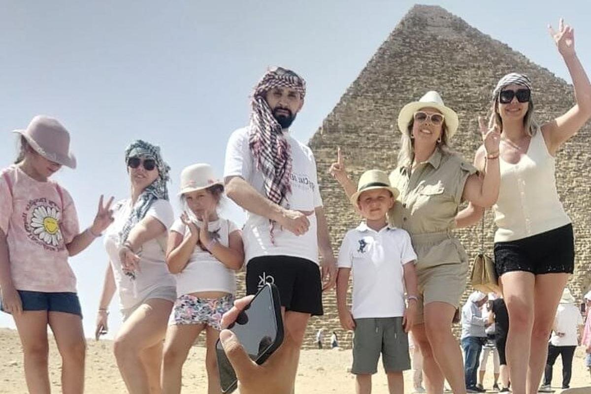 skupina lidí stojící před pyramidami