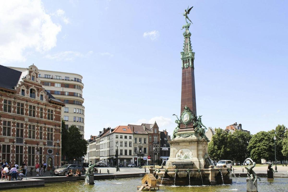 uma fonte no meio de uma cidade com uma torre do relógio