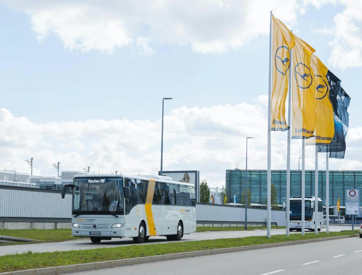 beli avtobus, ki se pelje po cesti poleg stavbe