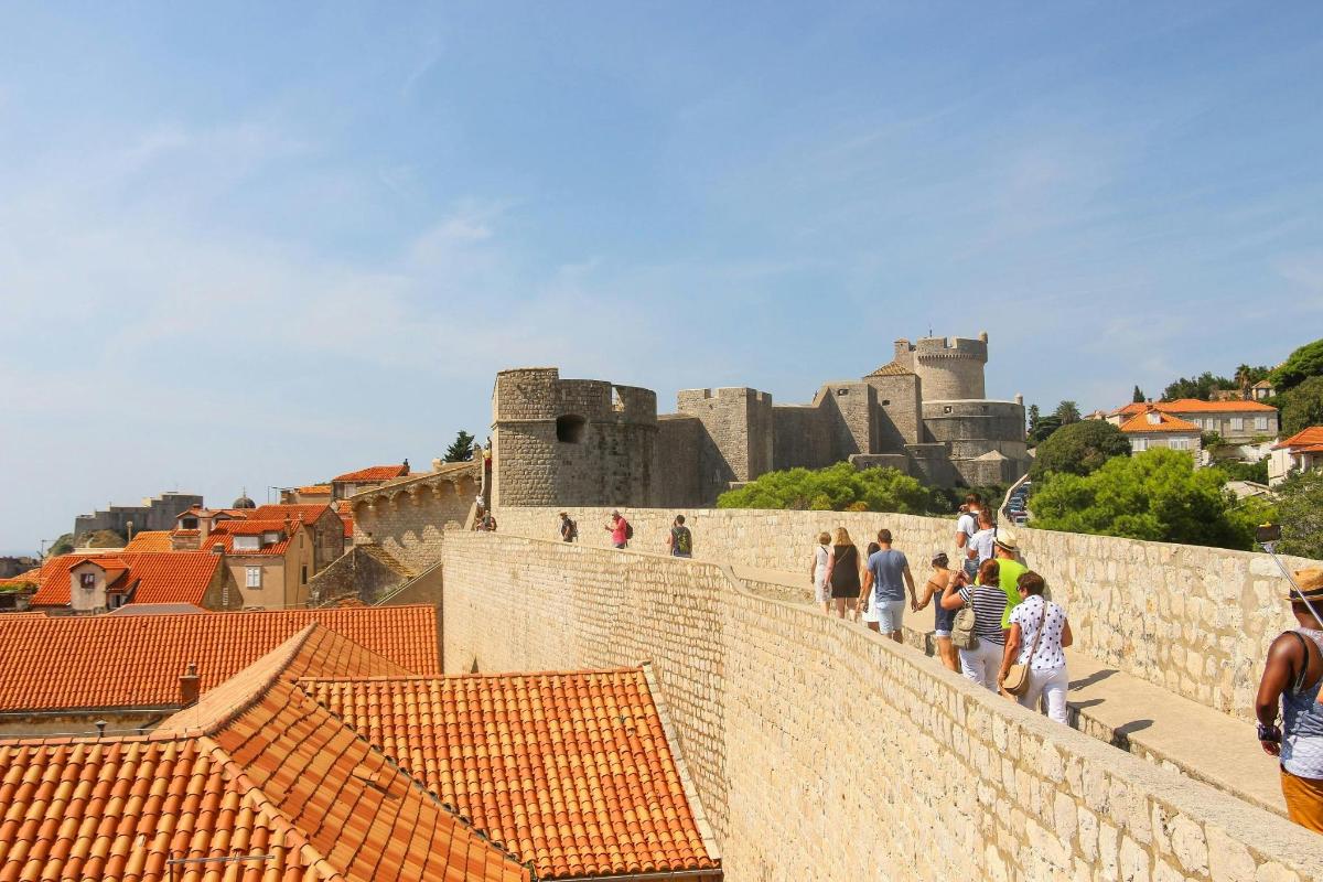 a group of people walking on a wall with a castle in the background