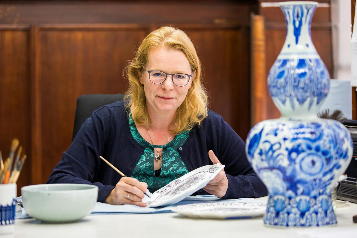 kona situr við borð með vasa