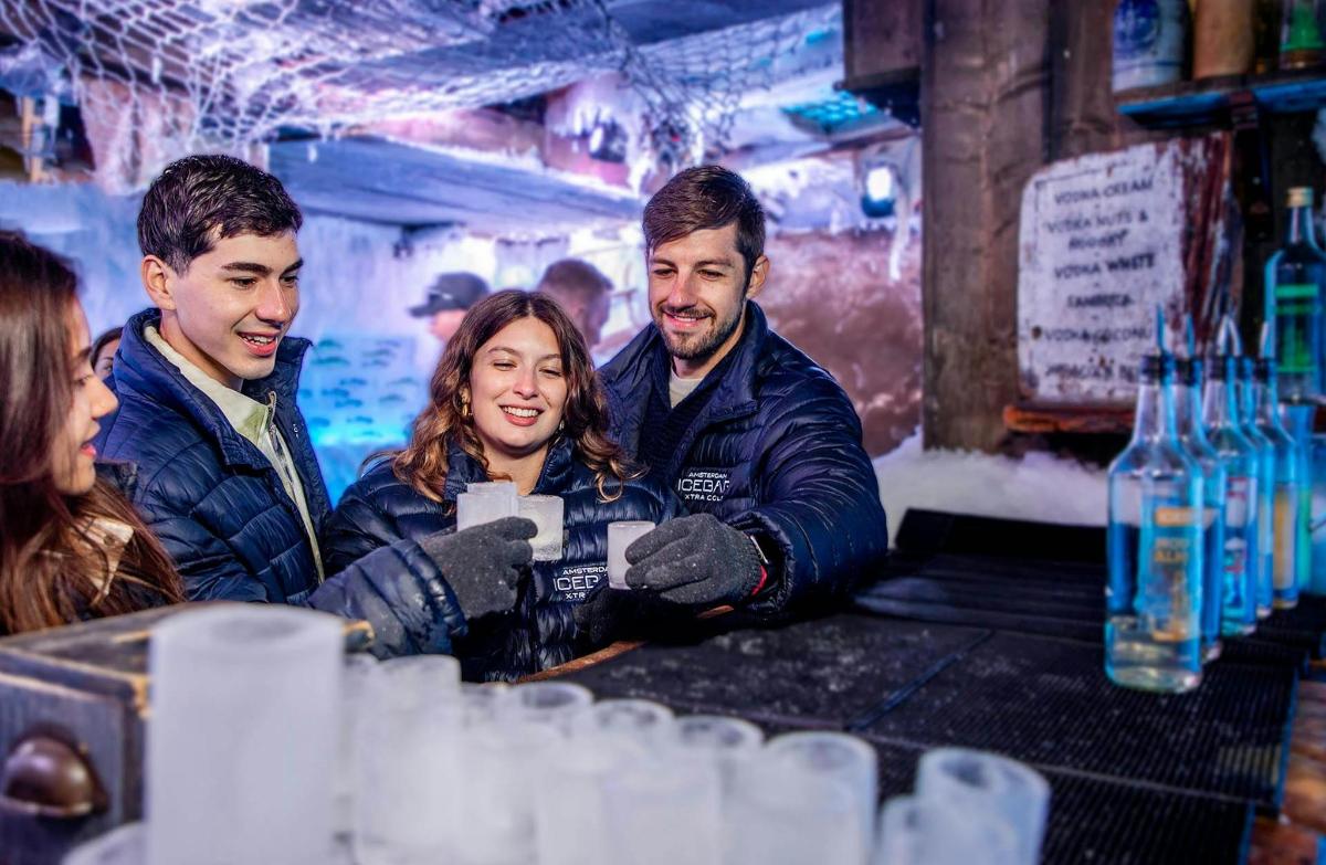 a group of three people standing at a bar