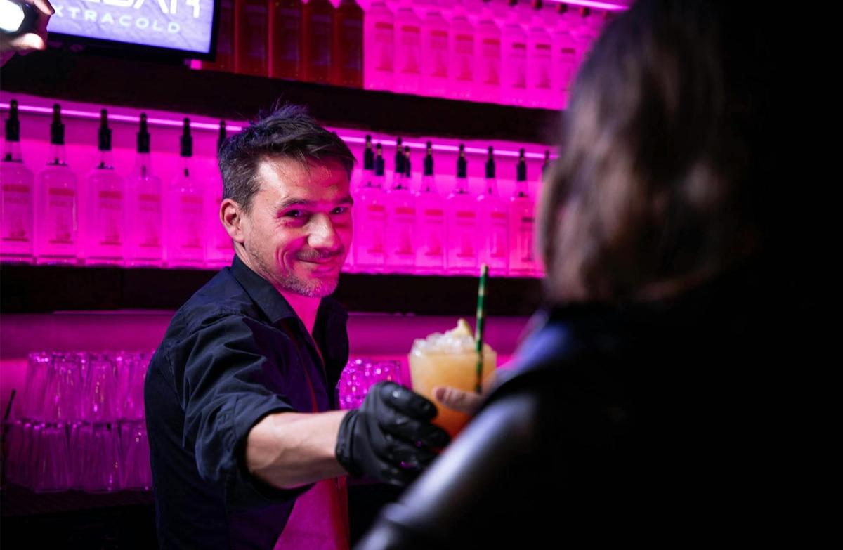 a man standing next to a woman holding a drink