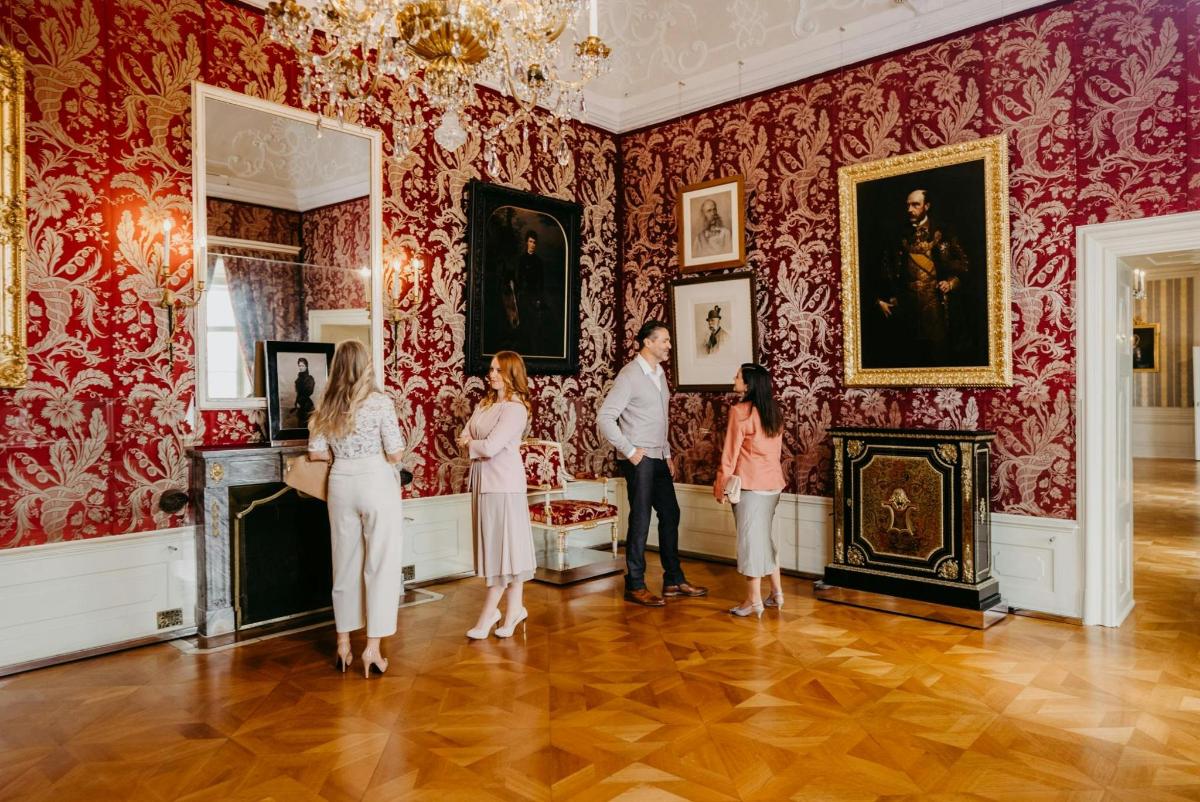 grupa ludzi stojąca w muzeum i oglądająca obrazy