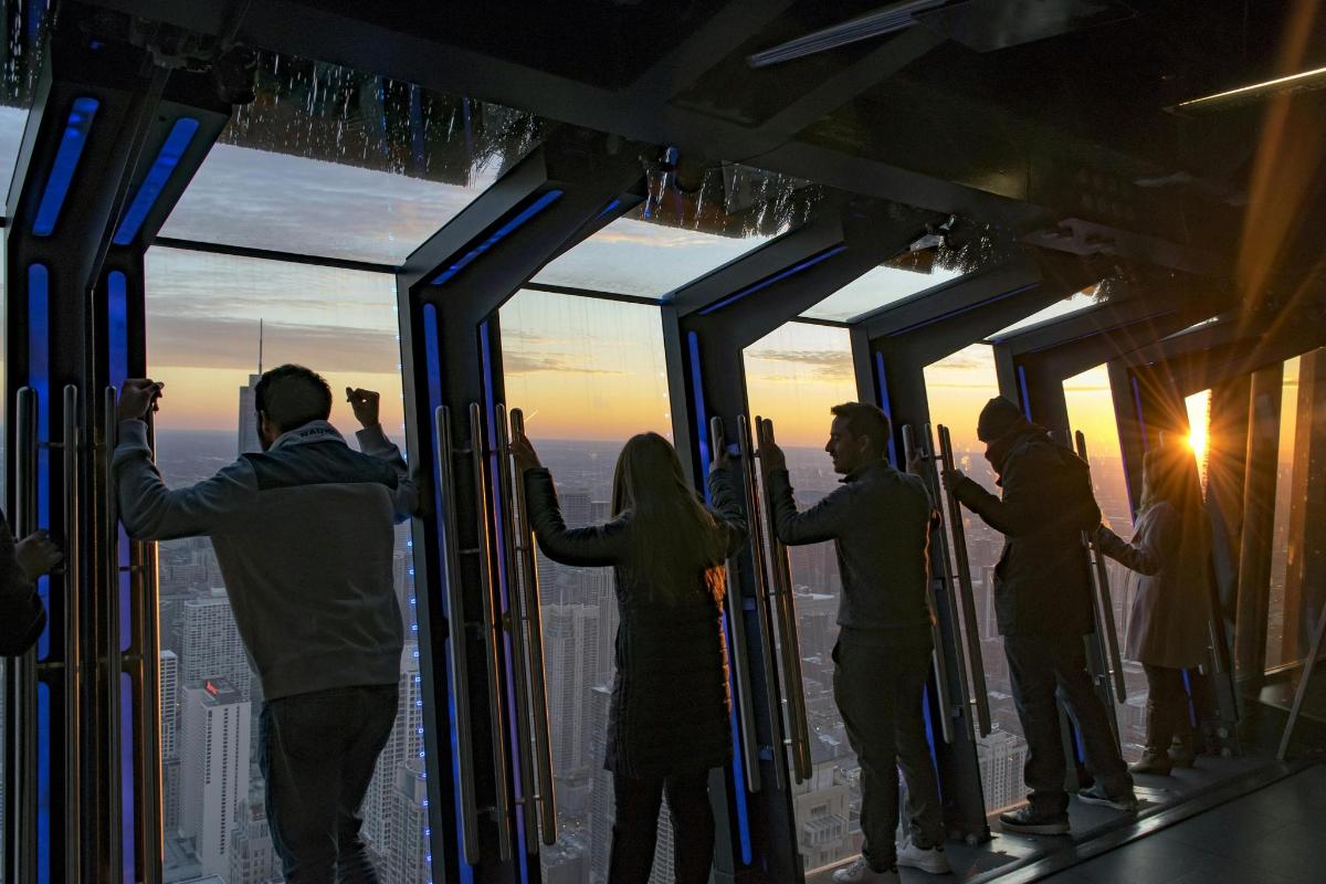 Un grupo de personas de pie frente a ventanas de vidrio.