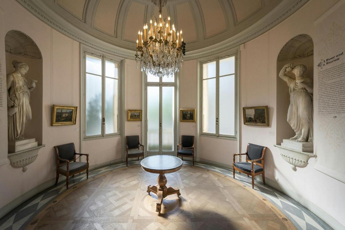 een kamer met een kroonluchter, een tafel en enkele beelden