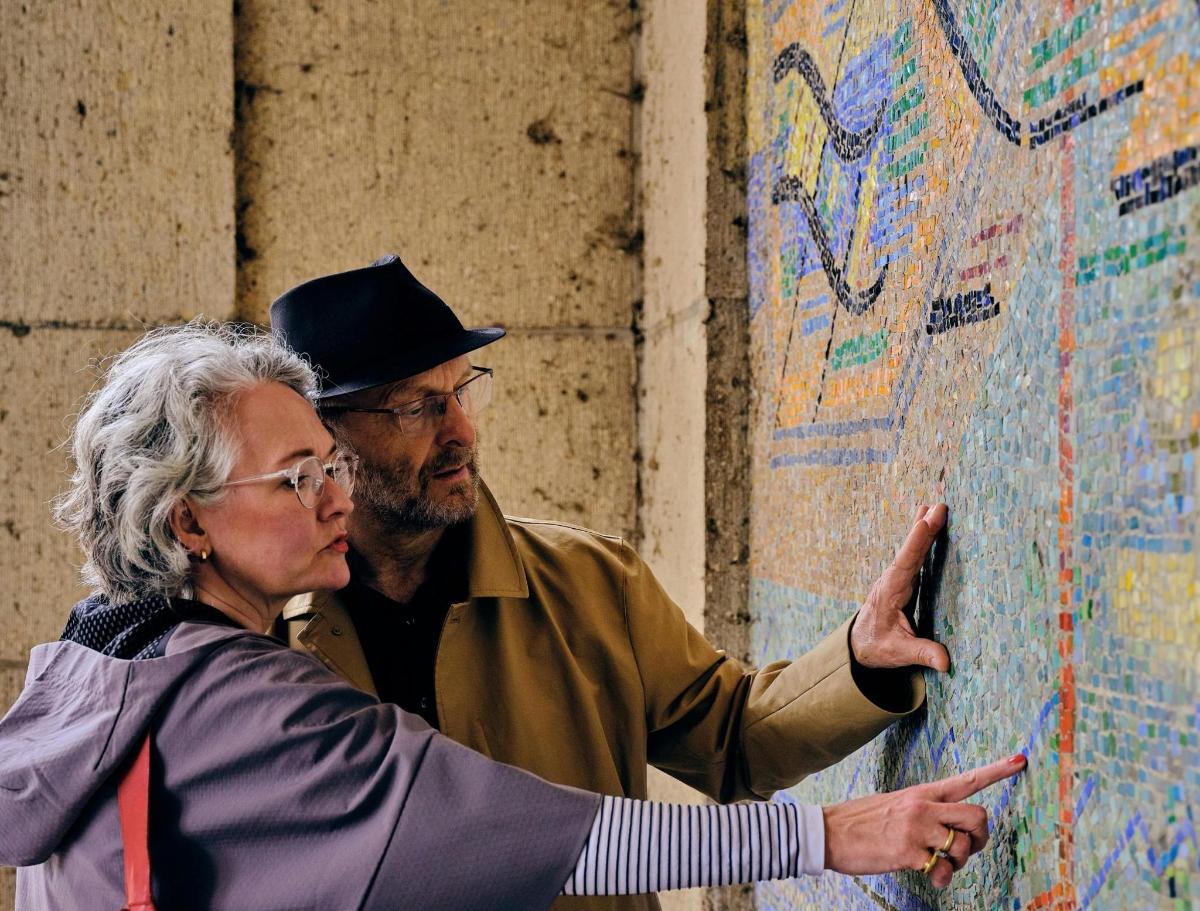 a man and a woman pointing at a wall