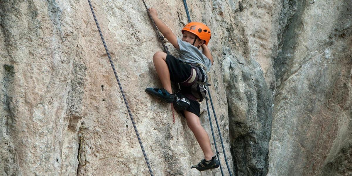 a man in an orange helmet climbing a rock wall