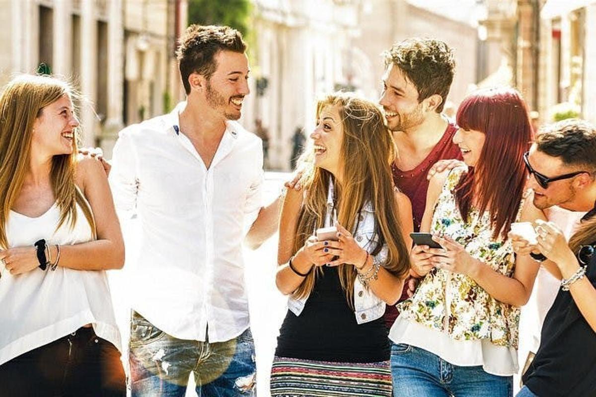 egy csoport ember sétál az utcán, akik a mobiltelefonjukat nézegetik