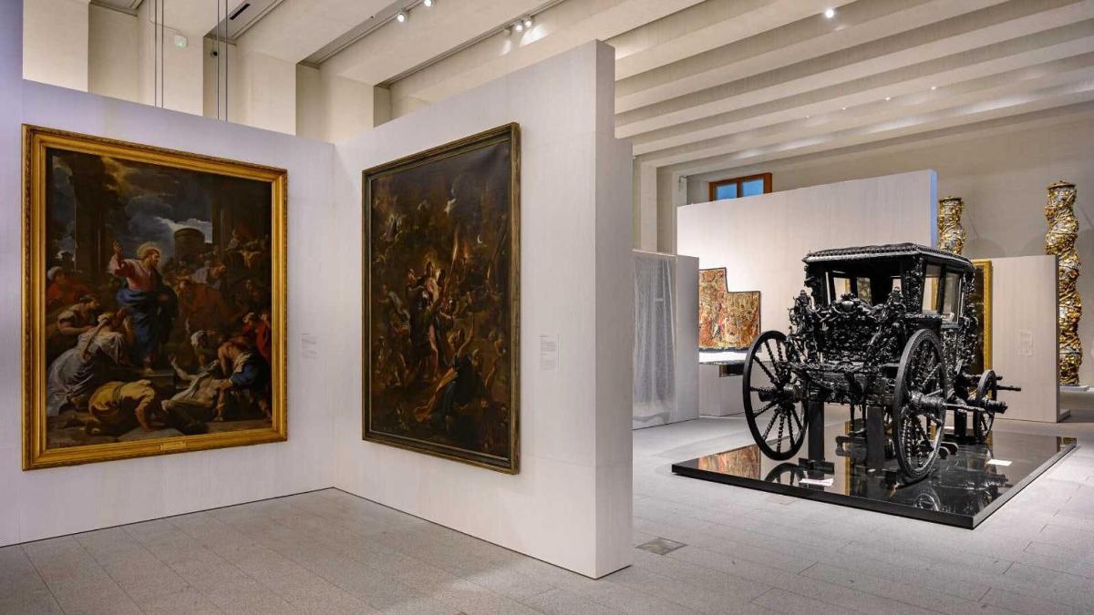 una sala de museu amb pintures i un carruatge exposats