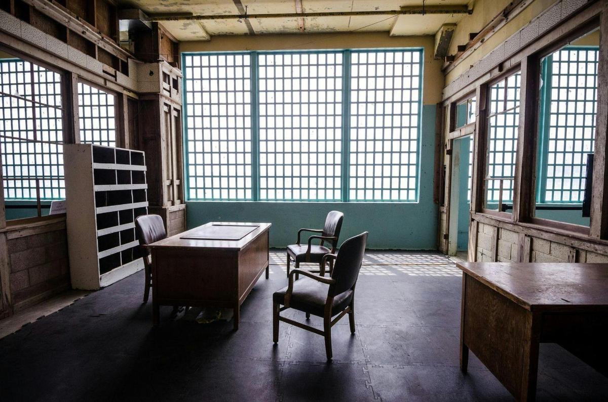 uma sala com cadeiras, uma mesa e janelas