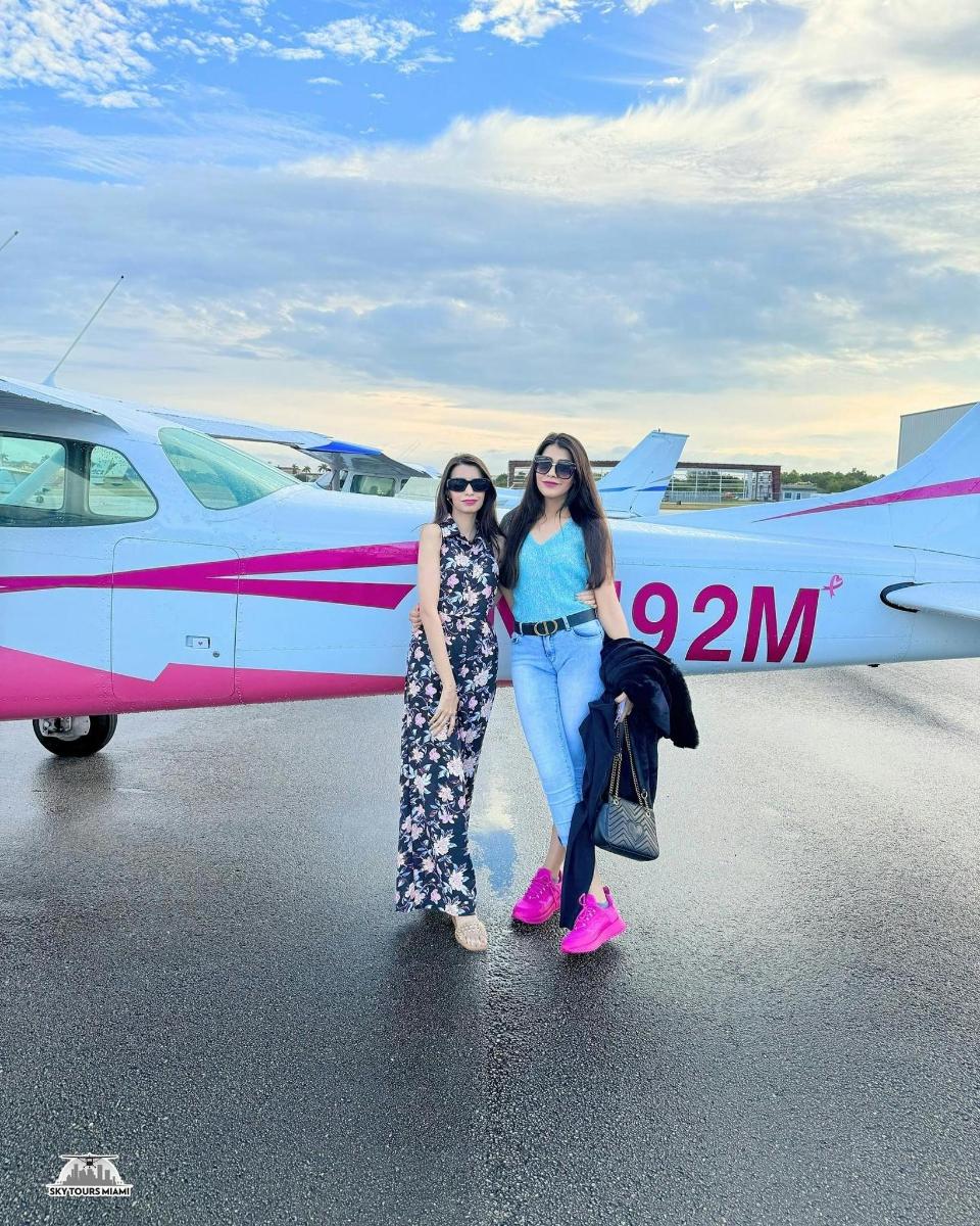 two women are standing in front of a plane