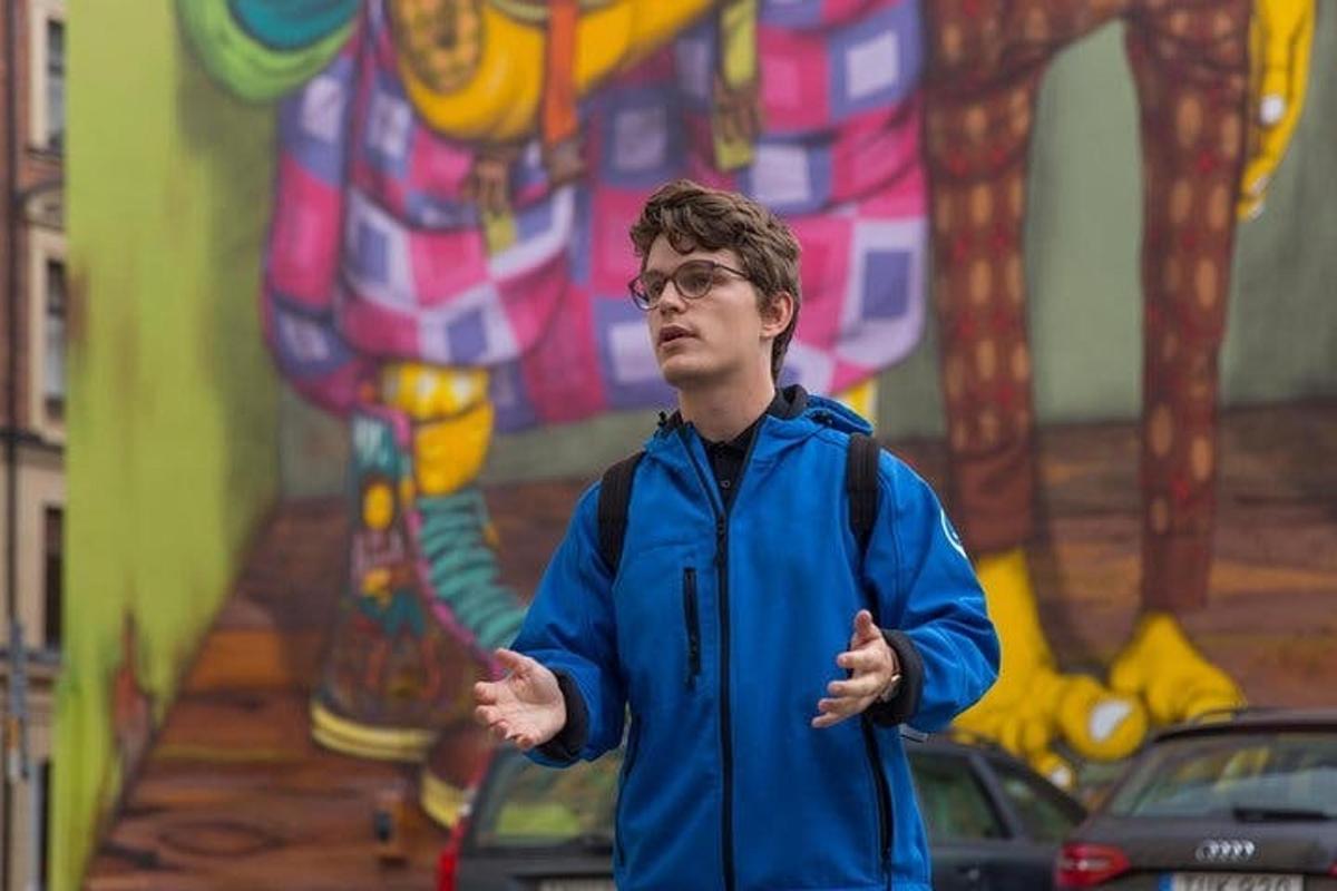 a man in a blue jacket standing in front of a mural