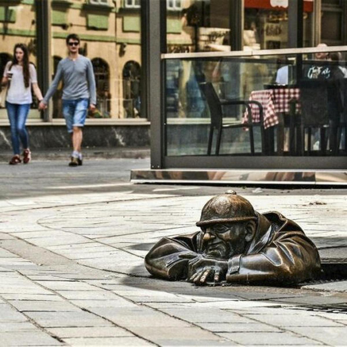 una estàtua de bronze d'un home estirat al carrer