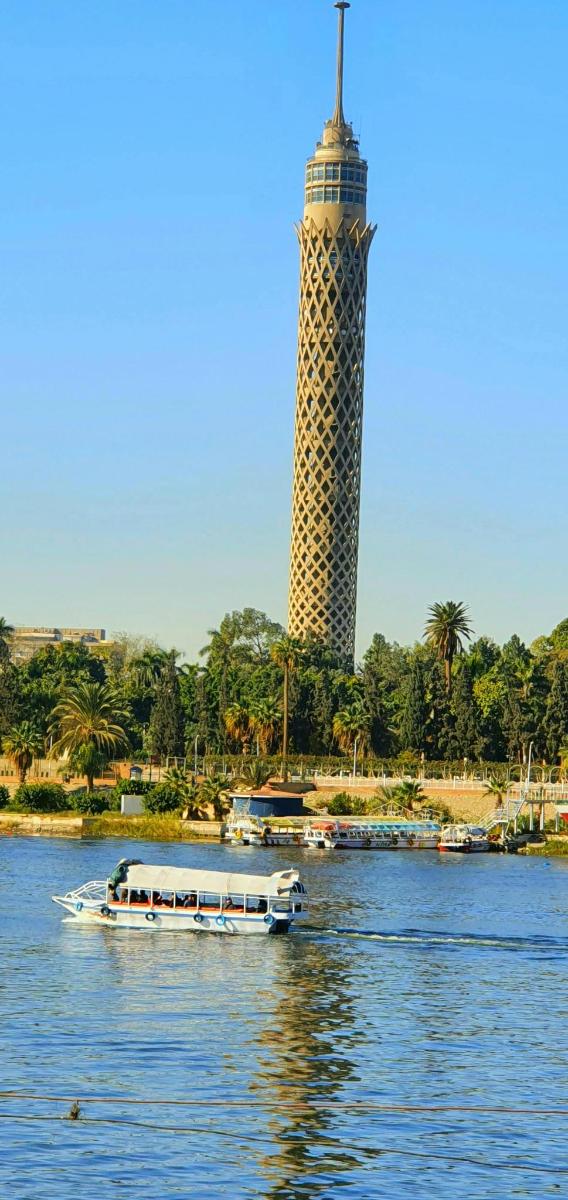 Un barco en el río con una torre al fondo.