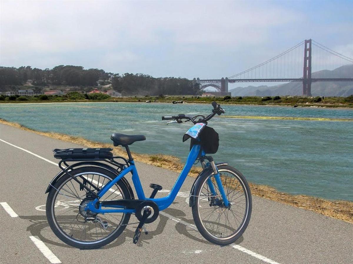 una bicicletta blu parcheggiata in un parcheggio vicino a un ponte