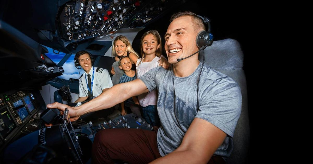 a man wearing headphones sitting in a cockpit with a group of people