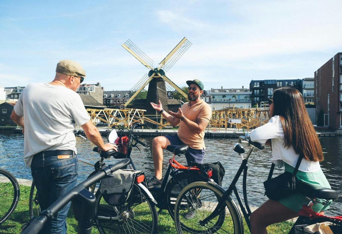 um grupo de pessoas em bicicletas ao lado de um moinho de vento