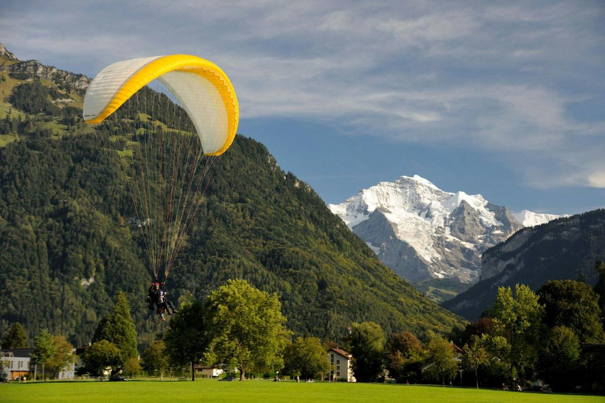 Žlutý a bílý padák letící nad polem s horami